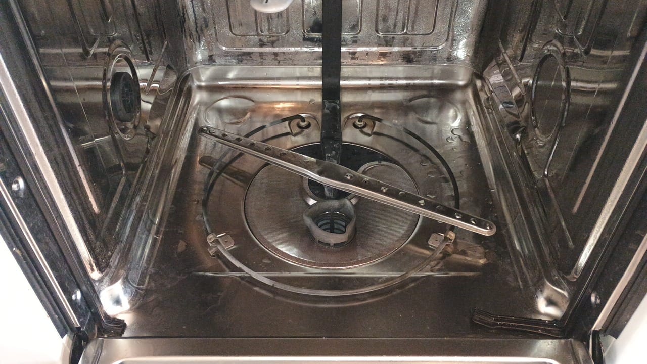 Dishwasher tub interior with spray arm and filter removed for cleaning
