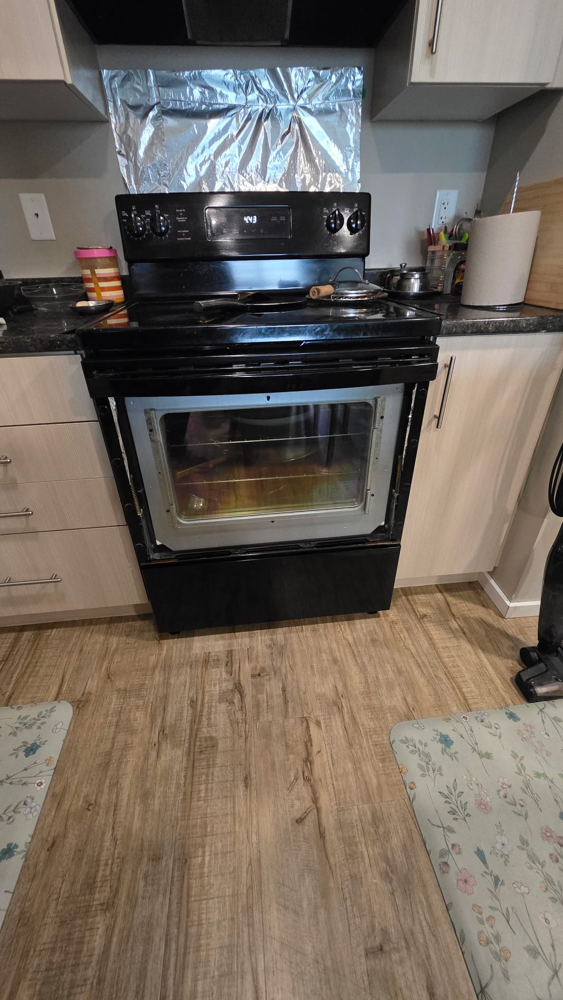 Electric range with oven door open mid-repair in a customer kitchen