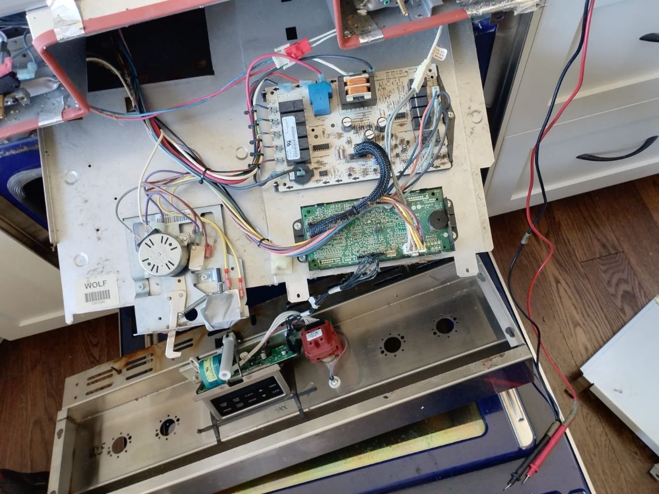 Range control panel opened up with the power board and display board exposed and a multimeter attached
