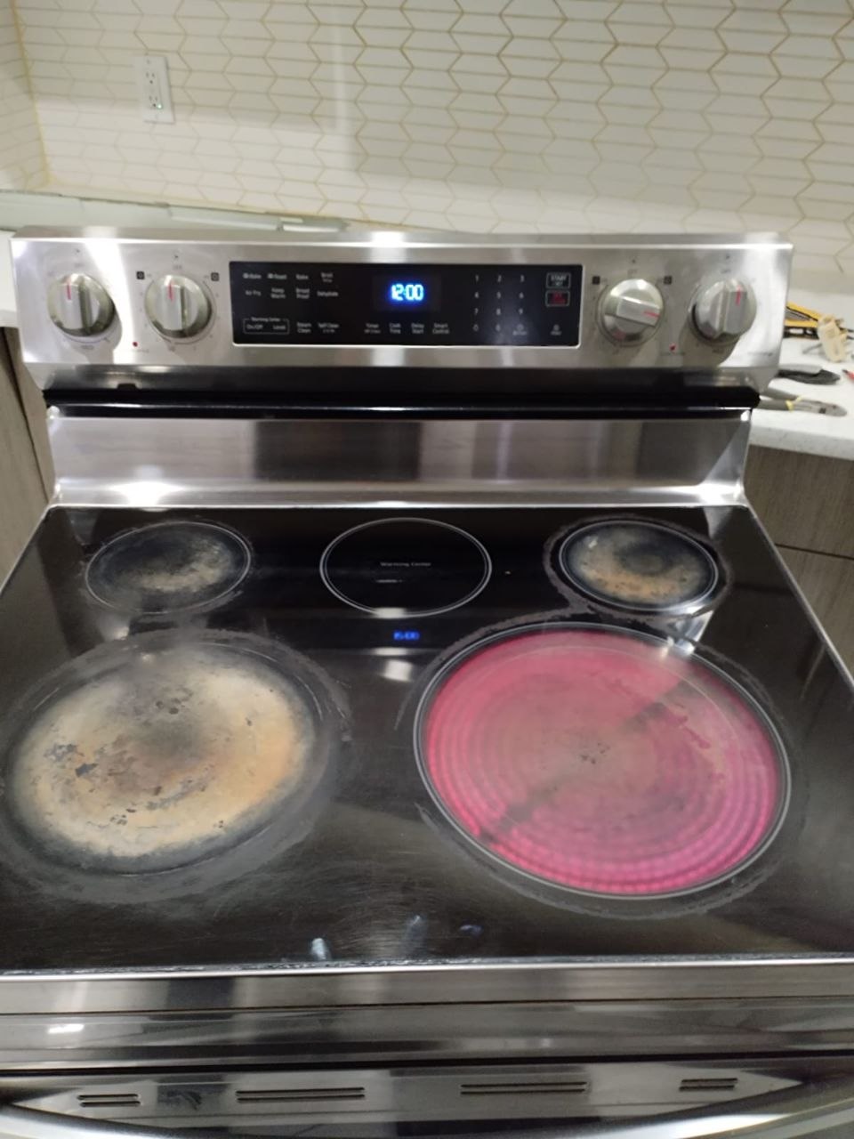 Stainless electric range with a glowing cooktop element during testing